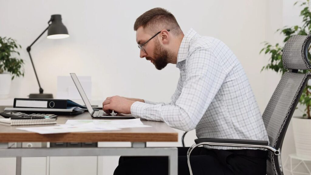 Mann sitzt am Tisch mit gebückter Haltung