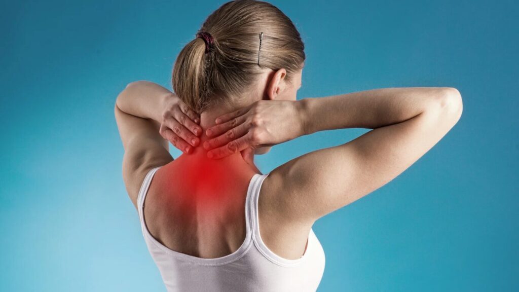 Frau, die sich an den Nacken fasst weil Schmerz 