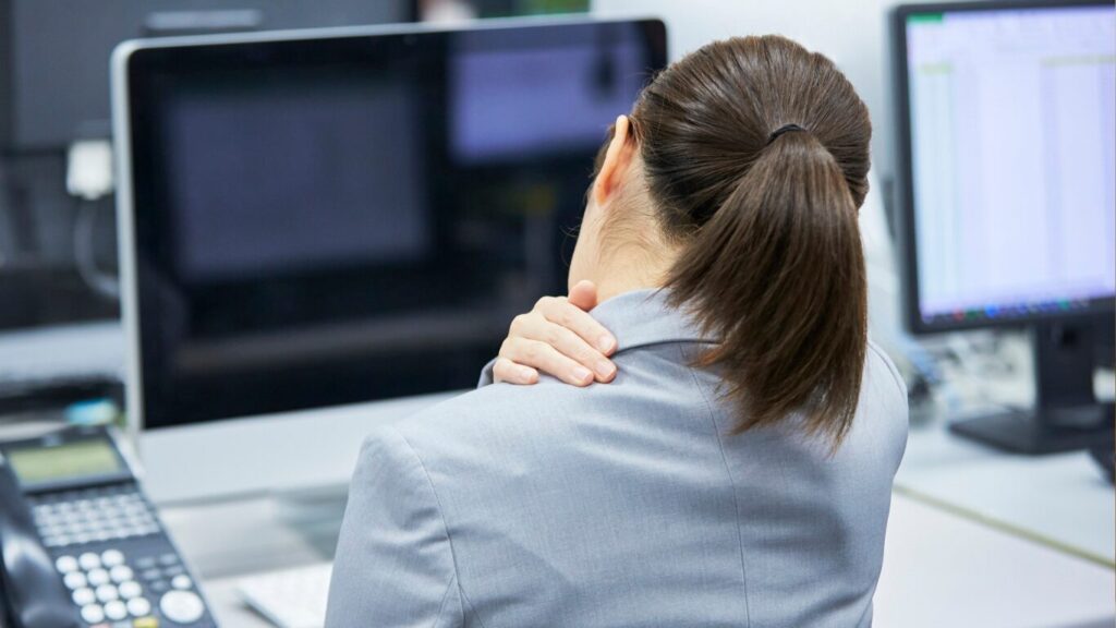 Frau greift sich an Schultern im Büro